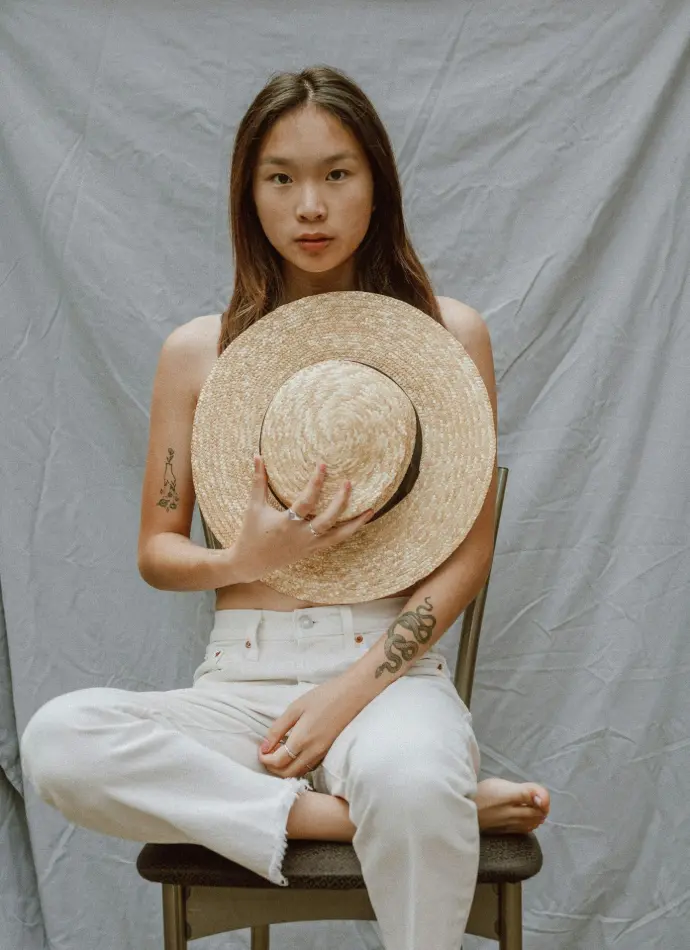 woman in white tank top and white pants wearing brown straw hat